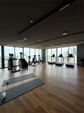 Fitness area featuring floor-to-ceiling windows, wood-finish flooring, and recessed ceiling lighting