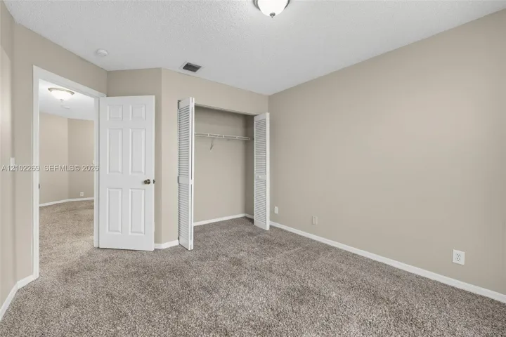 Neutral-toned interior featuring wall-to-wall carpeting, a reach-in closet with louvered bifold doors, and a paneled interior door
