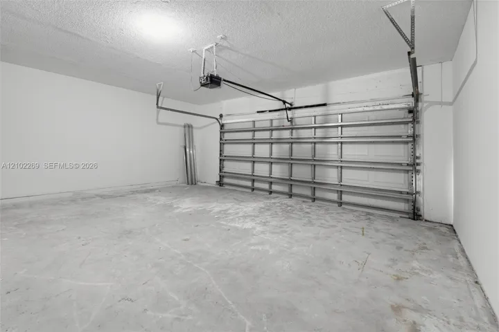 Enclosed garage featuring finished white walls, a concrete floor, and an automated overhead door system