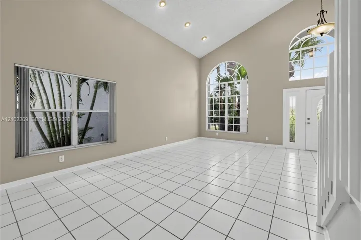 Vaulted ceilings, large arched windows, ceramic tile flooring, recessed lighting, and a front entry door with glass sidelights