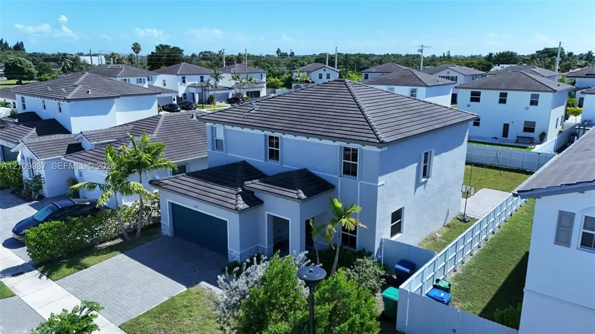 Two-story exterior featuring a hip roof with tile shingles, stucco siding, and a paved driveway