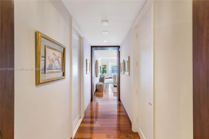 Hallway featuring wood-finish flooring, recessed ceiling lighting, and dark-toned door casings