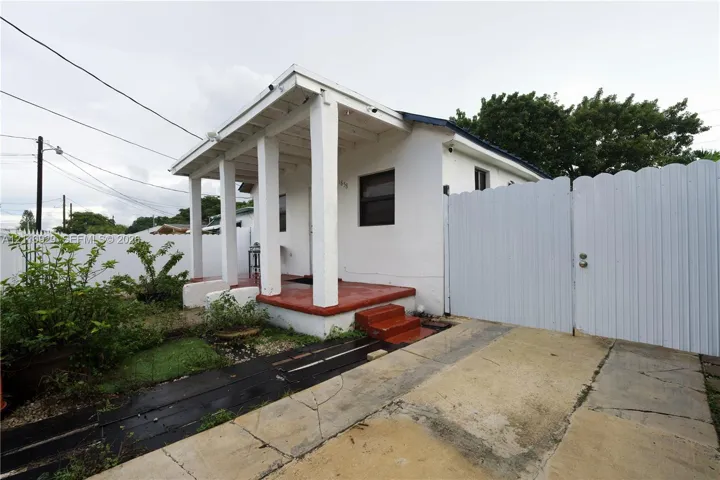 Exterior facade featuring a covered front porch, structural columns, painted concrete steps, and a white privacy gate