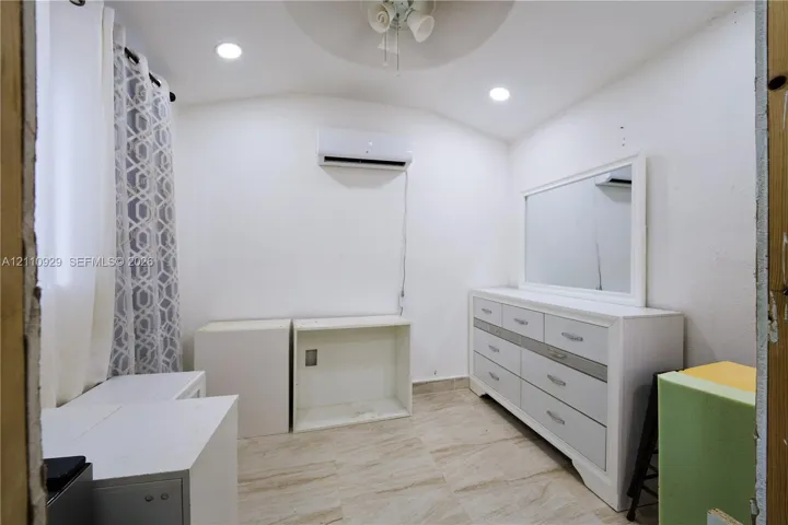 Room featuring recessed ceiling lighting, a wall-mounted ductless air conditioning unit, and tile flooring