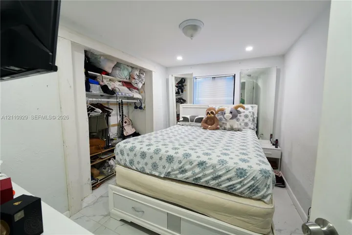 Bedroom featuring white marble-finish tile flooring, recessed lighting, and a built-in recessed closet