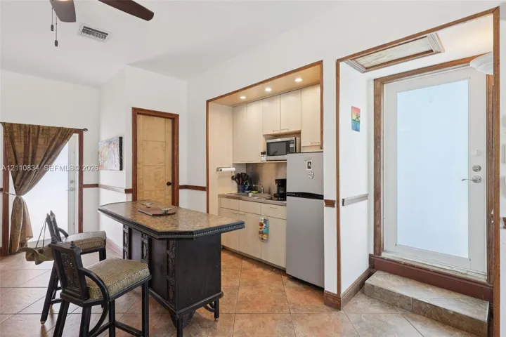 Kitchenette featuring light-finish cabinetry, stone-top counter island, ceramic tile flooring, built-in recessed lighting, and exterior doors