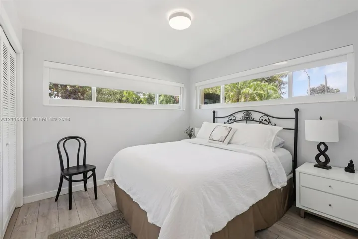 Neutral-toned interior featuring wood-finish flooring, horizontal sliding windows, and a built-in closet with bi-fold louvered doors