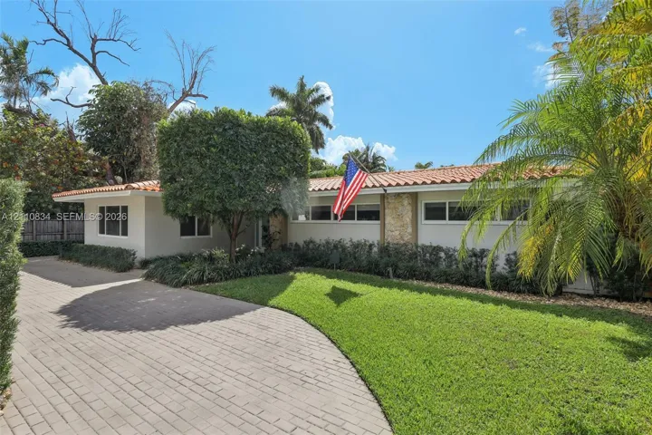Single-story exterior featuring a clay tile roof, stone masonry facade accents, and a paved brick driveway