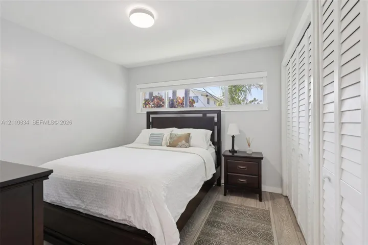 Neutral wall tones, wood-finish flooring, horizontal window, and floor-to-ceiling closet with louvered doors