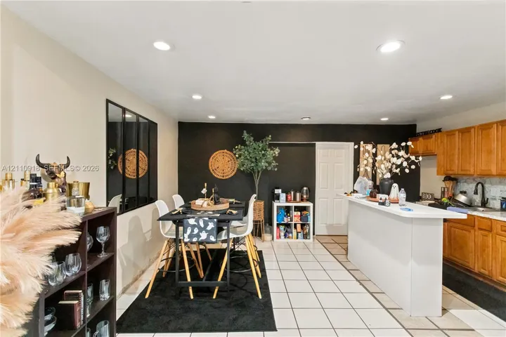 Kitchen featuring wood cabinetry, white countertops, a breakfast bar, recessed lighting, and tile flooring