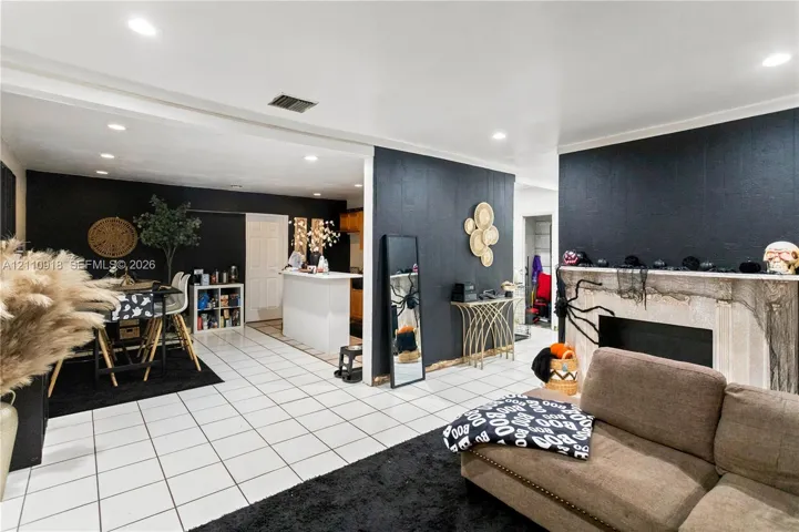 Open-concept interior featuring light-toned tile flooring, recessed ceiling lighting, and a fireplace with a stone-finish surround