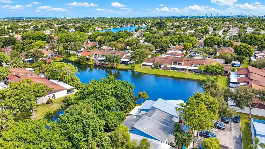 Aerial perspective featuring waterfront placement, mature tree canopy, and dense surrounding residential landscaping