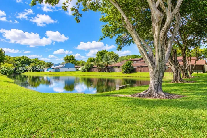Waterfront lot featuring a manicured lawn, mature shade trees, and perimeter privacy fencing