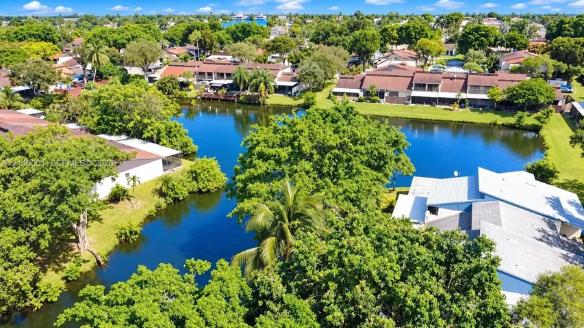Aerial perspective of waterfront residential grounds featuring mature shade trees, established landscaping, and expansive canal frontage
