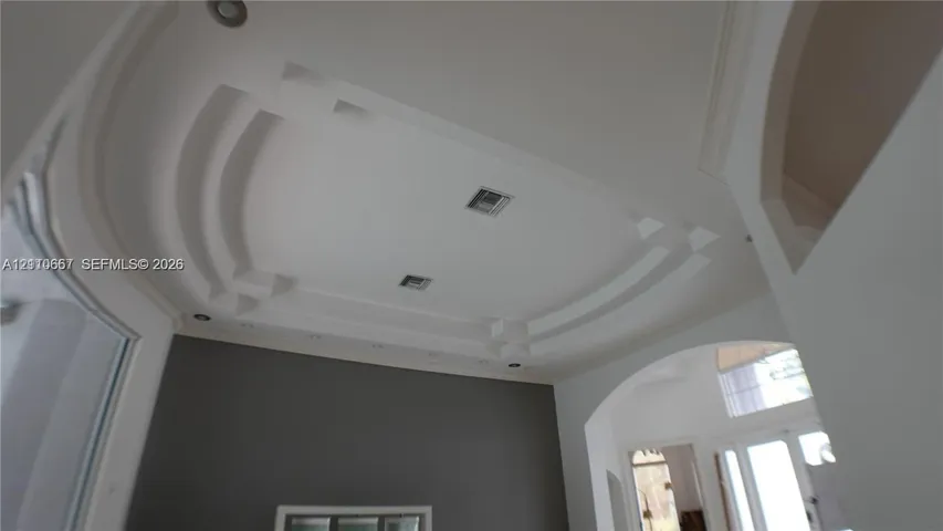 Custom tray ceiling with tiered architectural detailing, integrated recessed lighting, and arched passage entryways