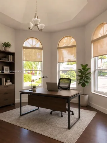 Vaulted ceiling, three arched windows, and wood-finish flooring