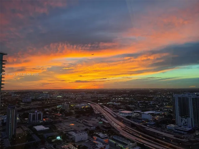 Elevated panoramic cityscape featuring a sunset backdrop