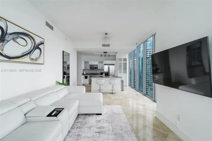 Polished stone flooring, floor-to-ceiling windows, modern kitchen with stainless steel appliances, and built-in glass cabinetry