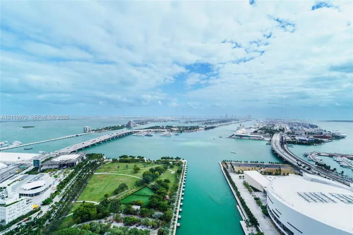Aerial perspective showcasing expansive water frontage, multiple bridge spans, an urban park, and harbor proximity