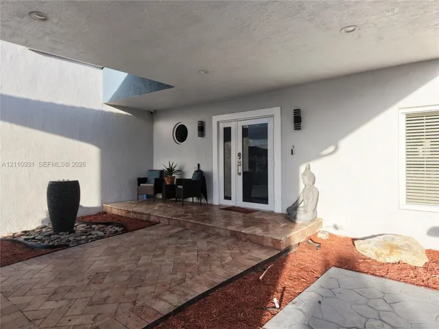 Covered entryway featuring herringbone-pattern tile flooring, double-door entry, recessed lighting, and a circular accent window