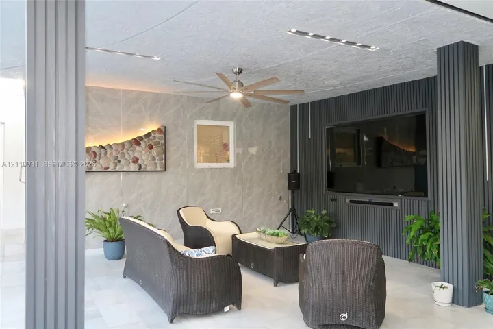 Covered patio featuring large-format stone-finish wall tiling, vertical ribbed accent paneling, recessed ceiling lighting, and a ceiling fan