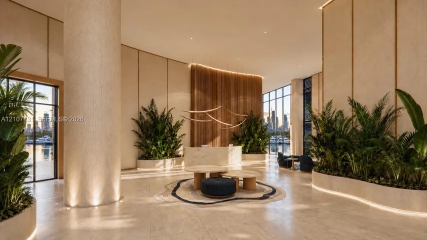 Grand lobby featuring stone flooring, floor-to-ceiling windows, integrated planter beds, vertical wood-slat wall paneling, and a stone-clad reception desk