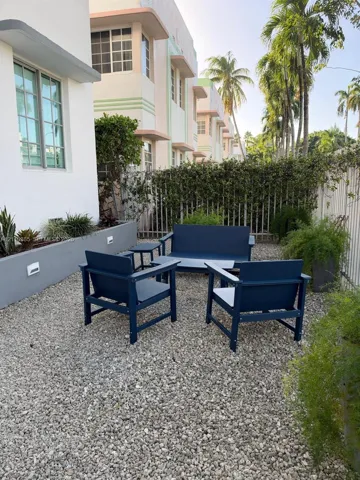 Exterior courtyard featuring decorative gravel ground cover, raised concrete planter beds, integrated low-voltage wall lighting, and metal perimeter fencing