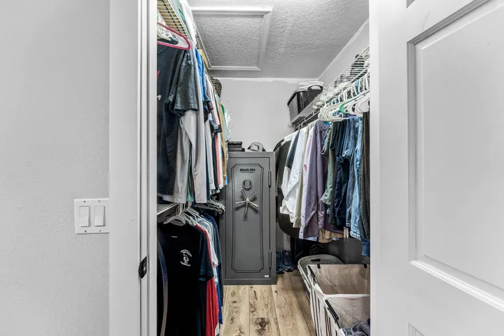 Walk-in storage area featuring wood-finish flooring and tiered wire shelving