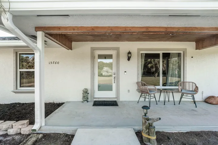 Covered front porch featuring a natural wood-finish ceiling, stucco exterior, sliding windows, and a glass-paneled entry door
