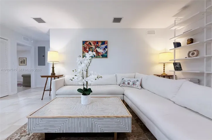 Living room area featuring tile flooring, neutral wall tones, and built-in white shelving