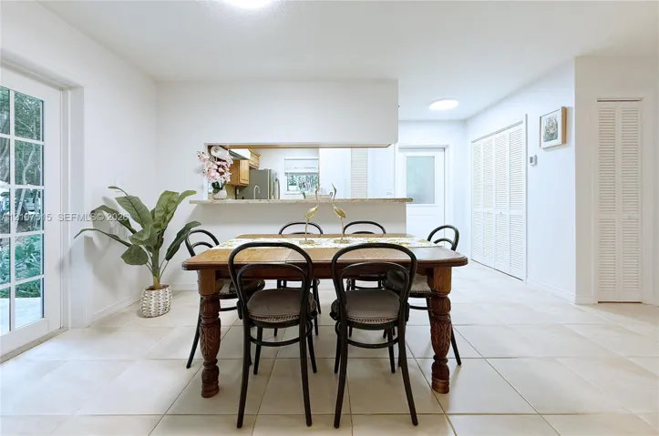 Entrance to dining area featuring light-toned tile flooring, recessed ceiling lighting, a pass-through opening, a full-lite glass door, and bi-fold closet doors by other entrance.