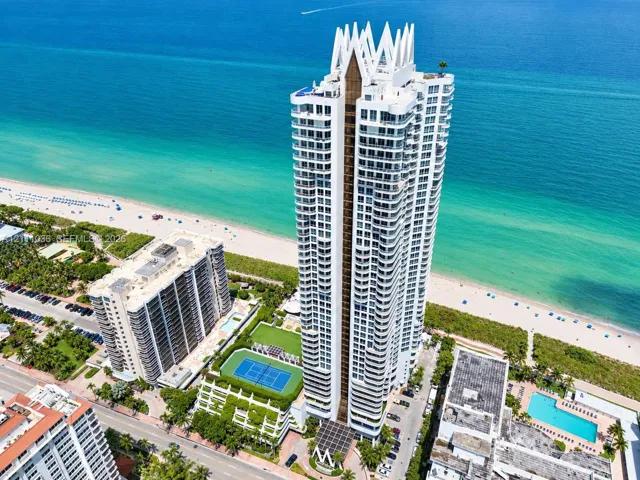 High-rise oceanfront tower featuring tiered architectural design, expansive balconies, a dedicated tennis court, and on-site swimming pools