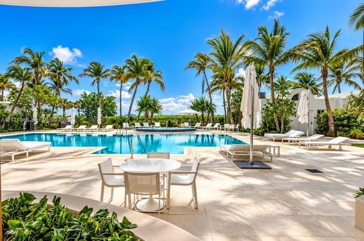 Swimming pool with integrated spa, expansive stone-paved deck, and mature palm trees
