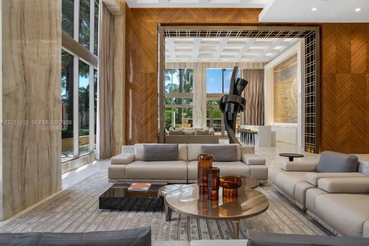 Double-height floor-to-ceiling windows, chevron-patterned wood wall paneling, coffered ceiling, stone-cladded columns, and decorative metal framework
