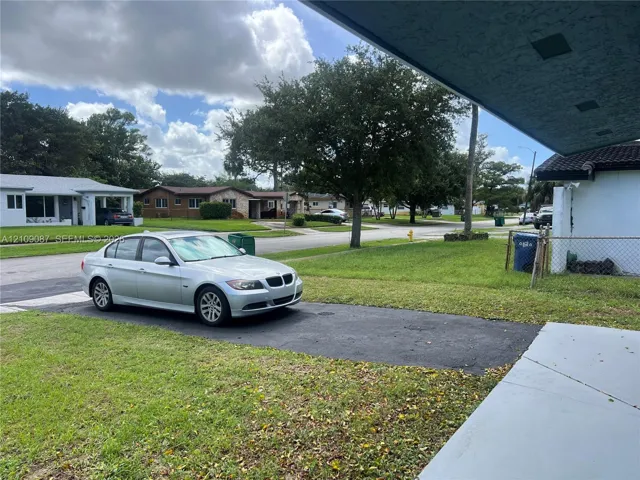 Asphalt driveway, covered entryway, and grass lawn