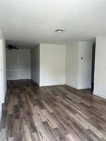 Interior space featuring wood-finish flooring, a multi-panel door, and a ceiling fan with integrated lighting