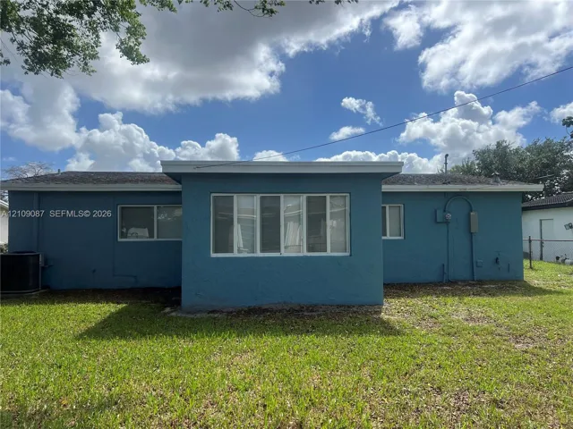 Single-story exterior featuring a stucco facade, multi-panel windows, and a level lawn
