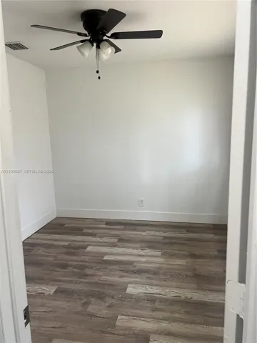 Room featuring wood-finish flooring, neutral walls, and a ceiling fan with integrated lighting