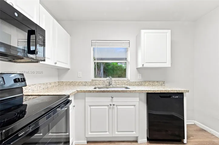 Kitchen featuring white cabinetry, stone-finish countertops, black built-in appliances, a stainless steel sink with a pull-down faucet, and wood-finish flooring