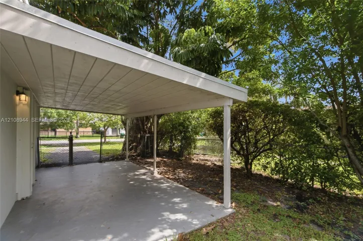 Covered concrete patio featuring a beadboard ceiling, wall-mounted exterior lighting, and support columns