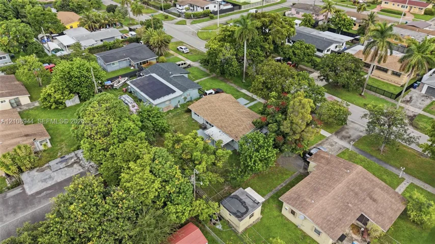 Aerial perspective featuring a residential lot with mature landscaping, a shingled roof, and a detached structure