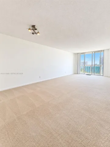 Open interior space featuring floor-to-ceiling glass sliding doors, wall-to-wall carpeting, and a multi-directional flush-mount light fixture