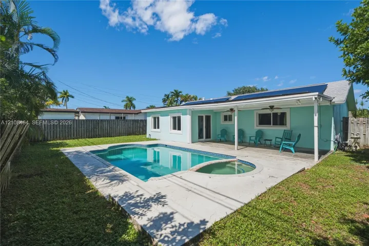 Backyard featuring a concrete pool deck, integrated in-ground pool and spa, covered patio area, and perimeter privacy fencing