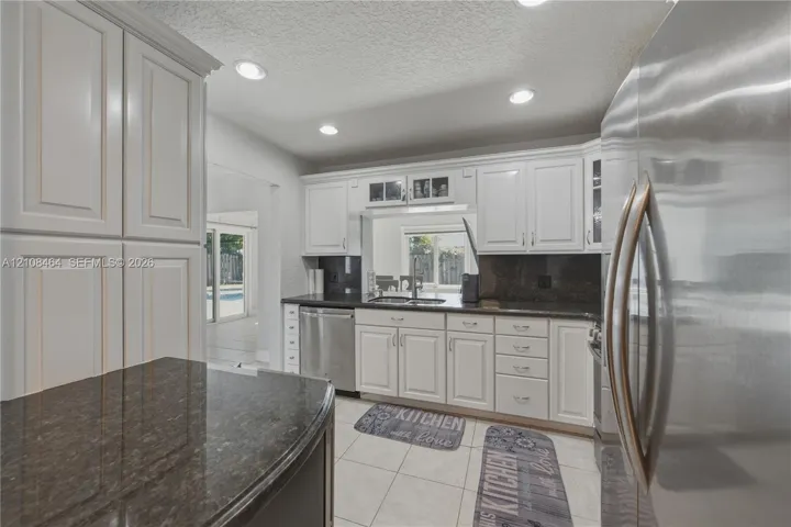 Kitchen featuring white cabinetry, dark stone countertops, stainless steel appliances, tile flooring, and recessed lighting