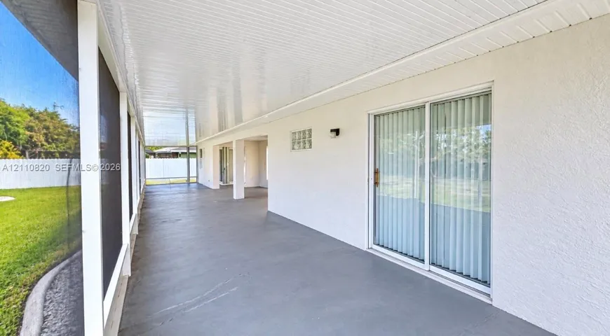 Screened-in lanai featuring a concrete floor, covered ceiling, glass block accent window, and sliding glass door