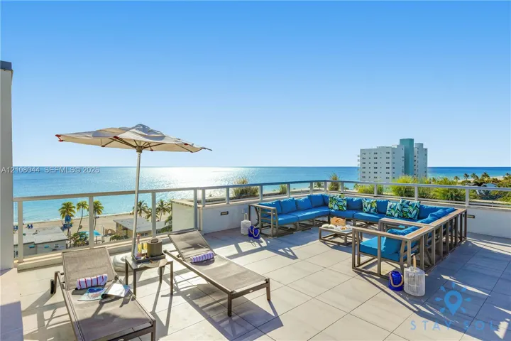Expansive open-air rooftop terrace featuring large-format tile flooring and a perimeter glass-panel railing