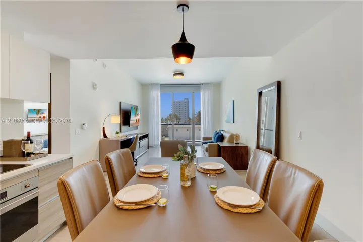 Kitchen area with built-in cabinetry, stainless steel oven, and light-toned wood-finish cabinetry, complemented by a hanging pendant light fixture and floor-to-ceiling glass doors