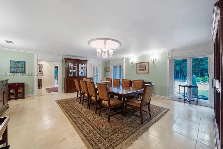 Dining area featuring large-format tile flooring, crown molding, a recessed ceiling medallion, an integrated chandelier, and floor-to-ceiling windows