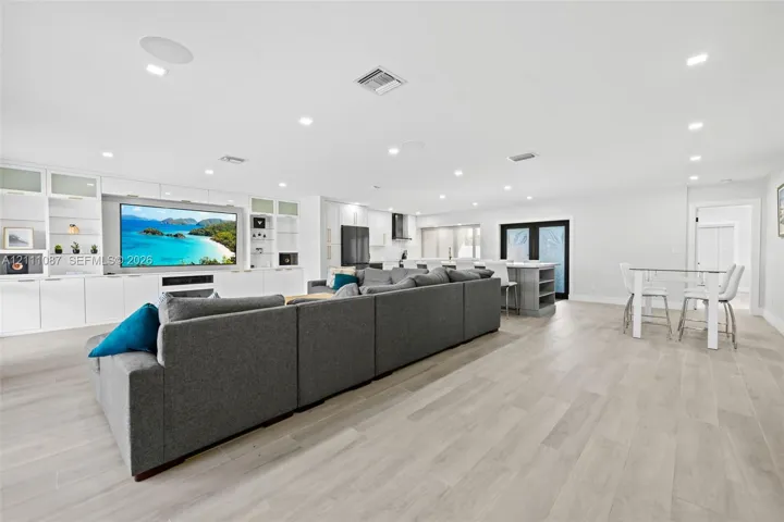 Open-concept living space featuring wood-finish flooring, recessed lighting, and custom floor-to-ceiling built-in cabinetry with integrated media center