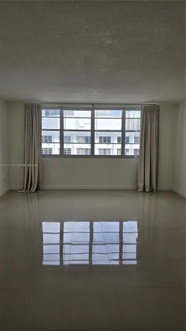 Large living area featuring polished tile flooring, neutral wall tones, and expansive multi-pane windows